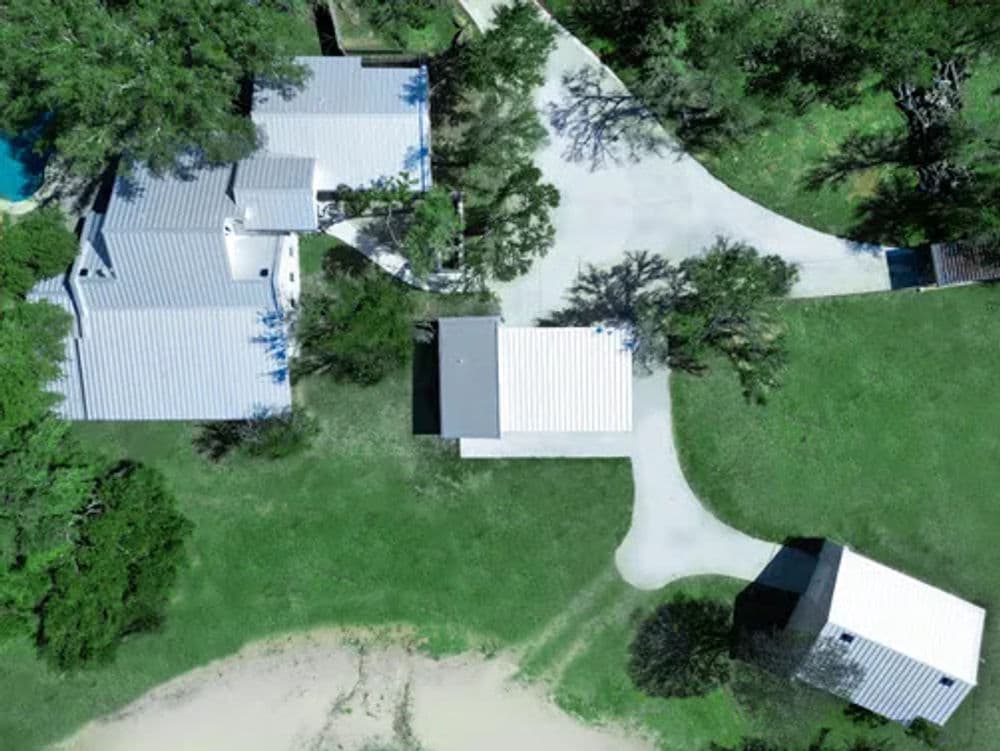 Aerial view of a residential property featuring multiple buildings and landscaped grounds.