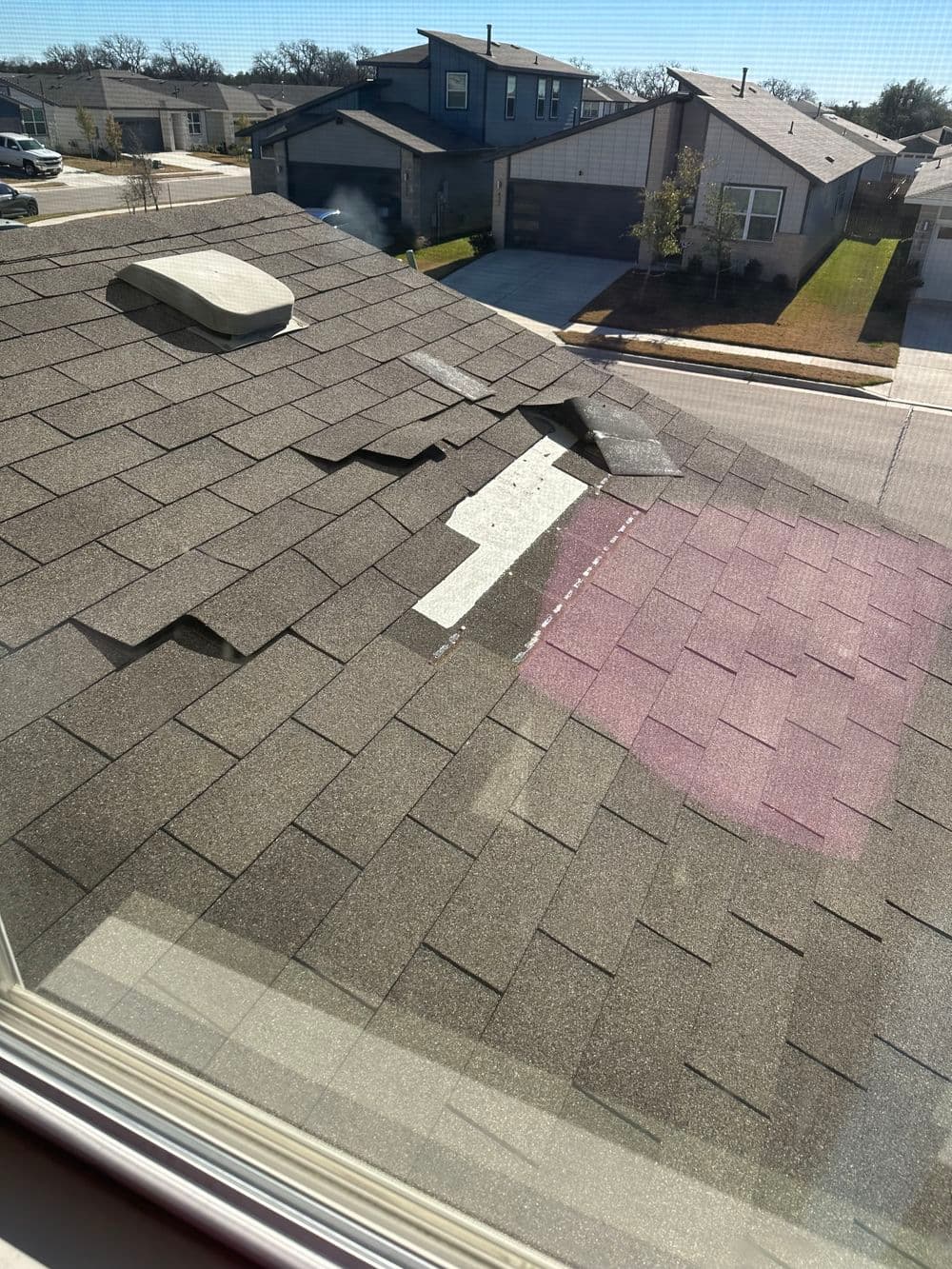 Damaged asphalt roof shingles with visible wear and tear from a second-story window view.