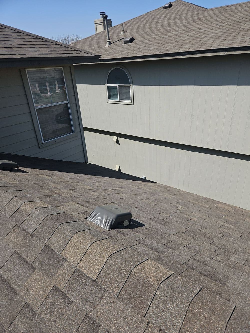 Aerial view of asphalt shingle roof with vent, highlighting modern home architecture.