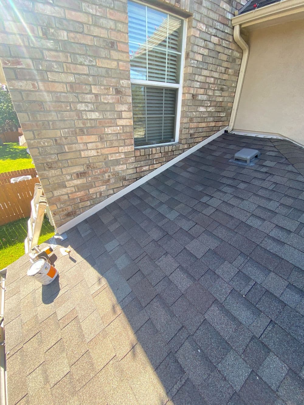 New asphalt shingle roof installation on a residential home with clear blue skies.