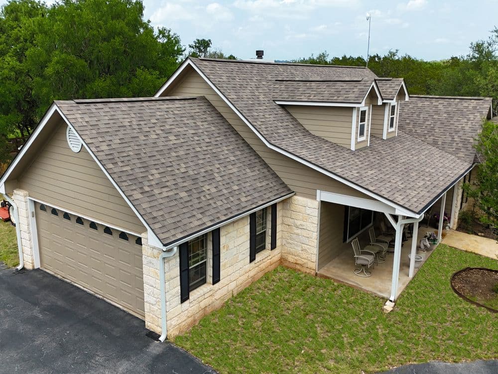 Spacious suburban home with a stone exterior and a two-car garage surrounded by greenery.