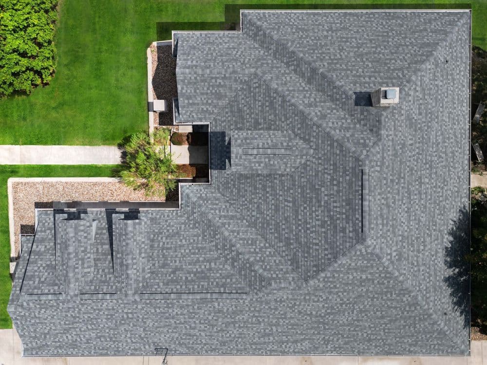 Aerial view of a gray shingle roof with landscaped yard and walkway.