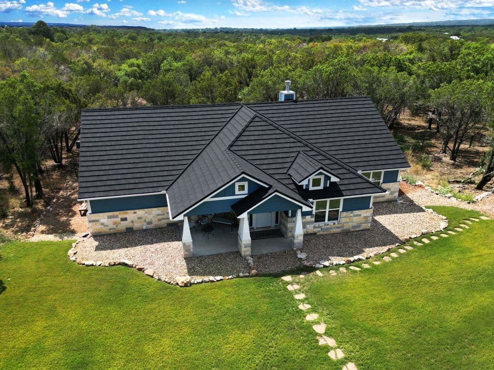 Aerial view of a modern house with stone accents, surrounded by green landscaping.